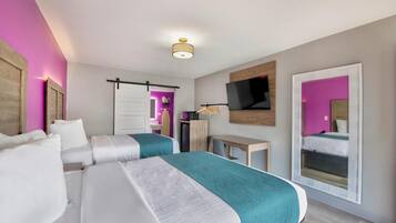 Une chambre d’hôtel avec deux lits, un téléviseur fixé au mur et une porte coulissante donnant accès à la salle de bain.