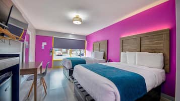 A hotel room with two beds, a desk, and a view of the street.