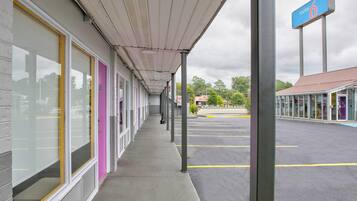A motel with a covered walkway, a parking lot, and a sign indicating the motel number.