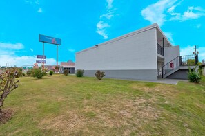 A modern building with a flat roof and a large sign indicating a motel. - 1 King Bed | Non-Smoking (Tuscaloosa)
