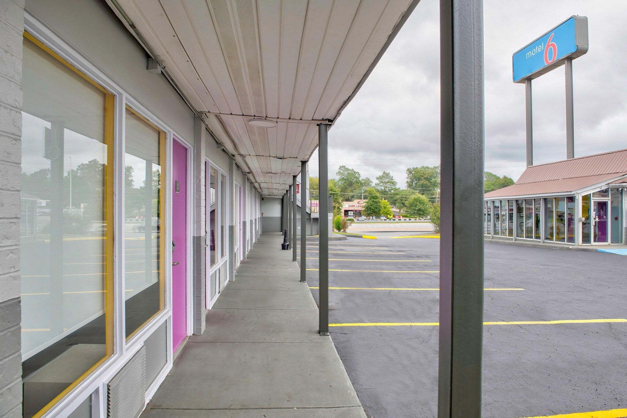 A motel with a covered walkway, a parking lot, and a sign indicating the motel number.