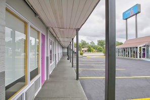 A motel with a covered walkway, a parking lot, and a sign indicating the motel number. - 1 King Bed | Non-Smoking (Tuscaloosa)