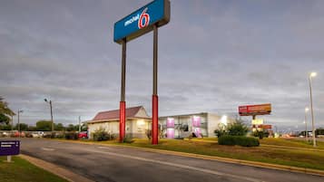 Un motel avec une enseigne bien visible, un service au volant et un parking.