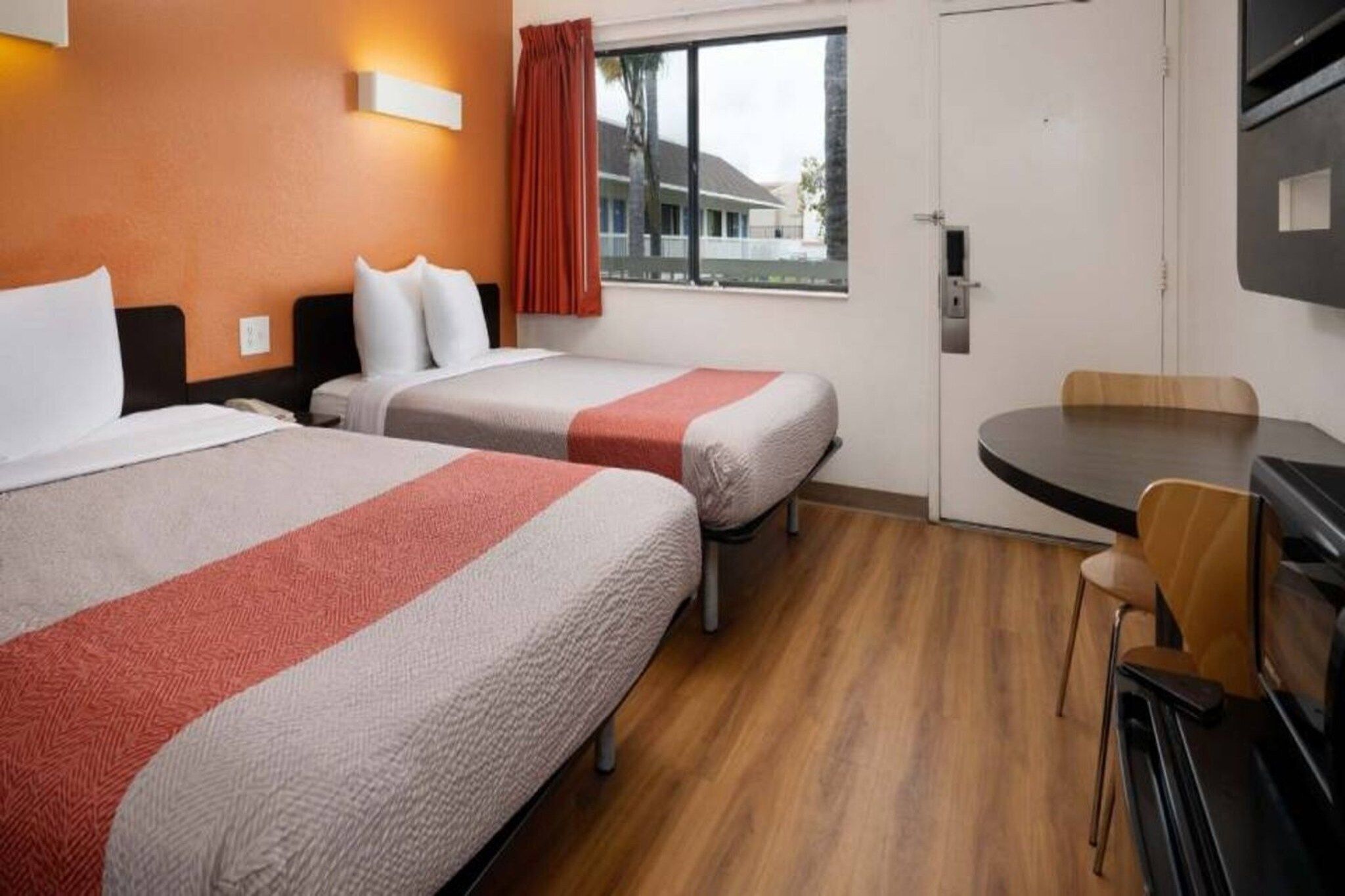A hotel room with two beds, a dining table, and a TV.