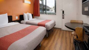 A hotel room with two beds, a dining table, and a TV.