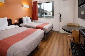 Ett hotellrum med två sängar, ett matbord och en TV.