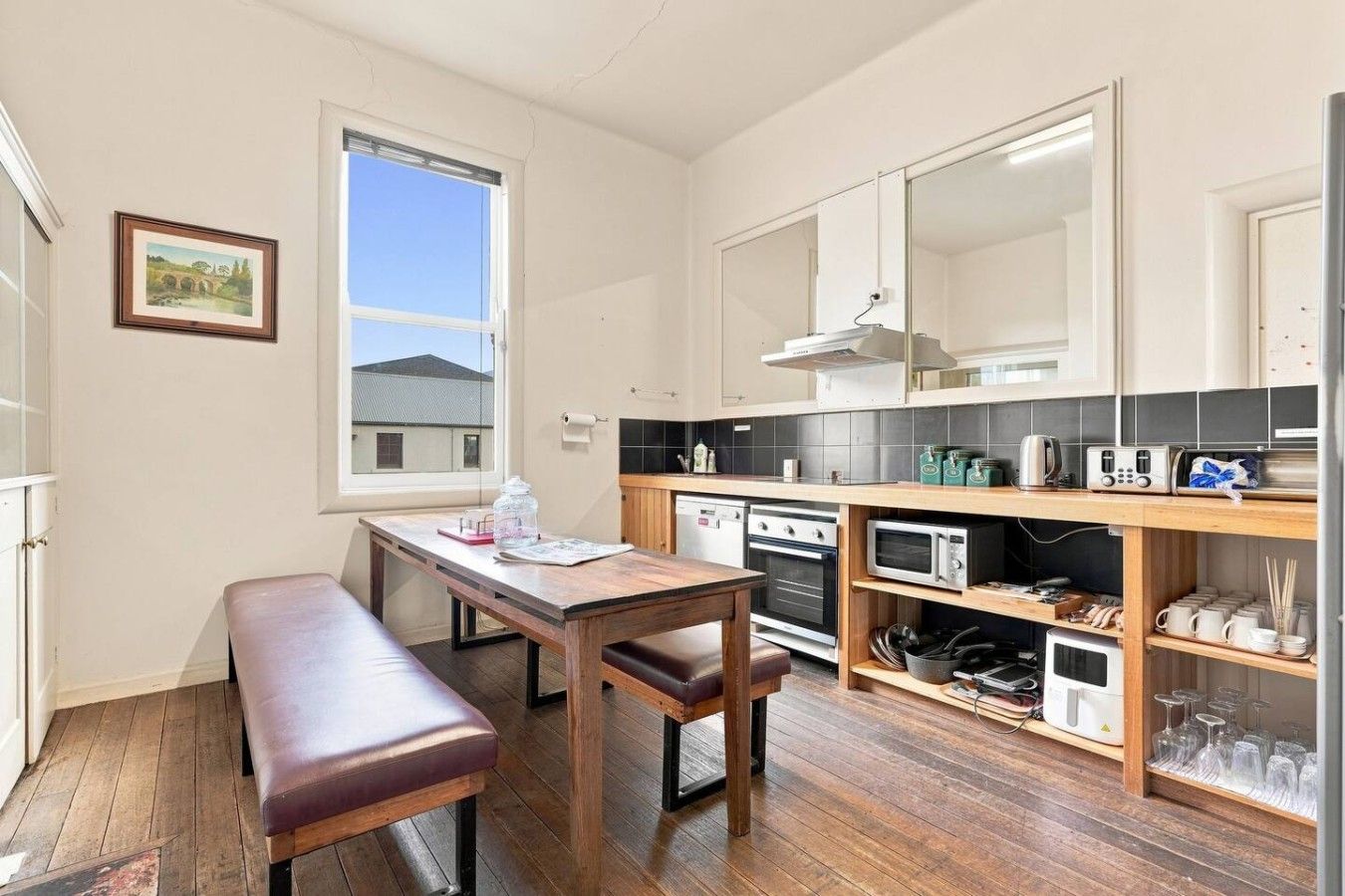 Une cuisine de taille réduite avec une table et un banc en bois, et une vue sur un pont à l’extérieur.
