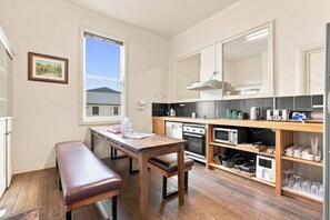 Een kleine keuken met een houten tafel, een bankje en uitzicht op een brug.