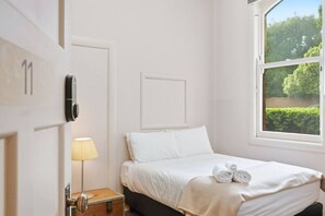 A bedroom with a bed, a bedside lamp, a window with a view of greenery, and a door with a lock. - Edinburgh - Double Room + Free Parking (Hobart)
