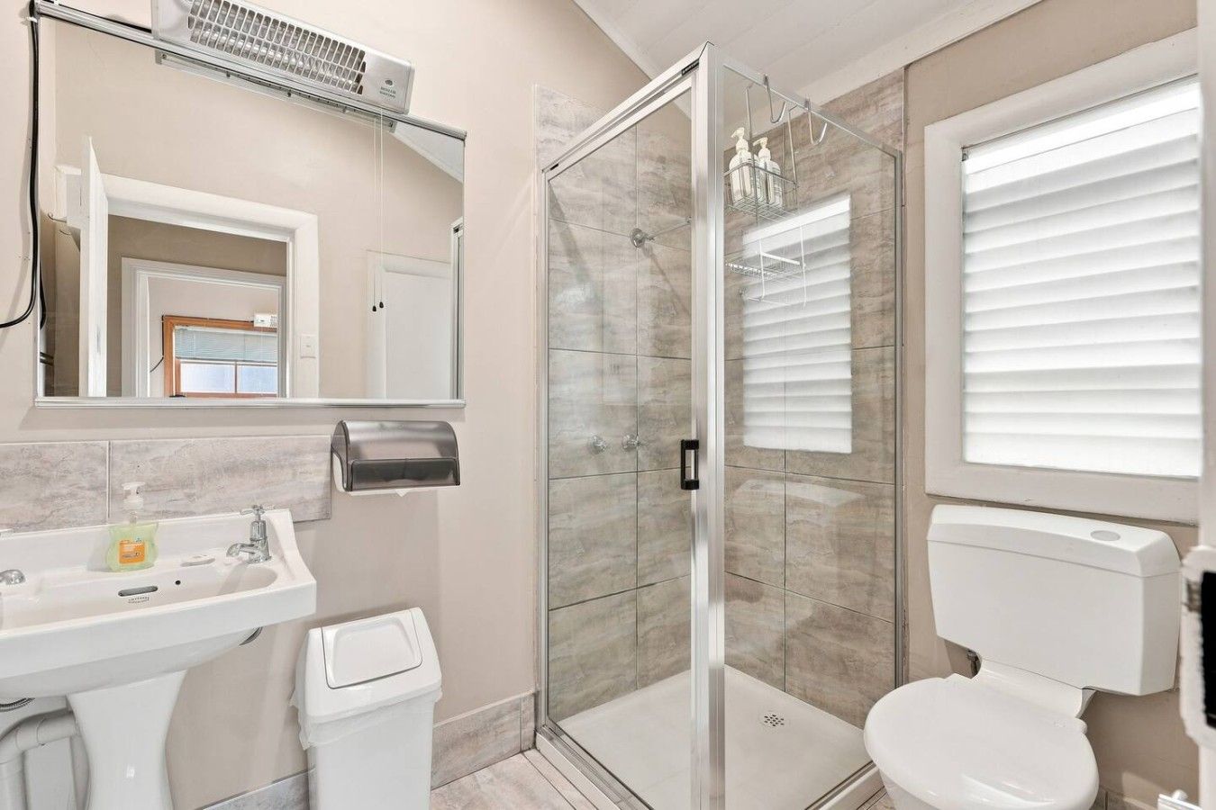 Un baño con ducha envuelta en vidrio, inodoro, lavabo y espejo.