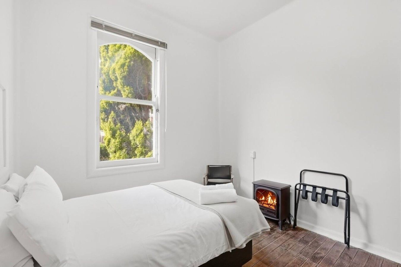 Une chambre à coucher avec un lit, une fenêtre, un téléviseur et un poêle à bois.