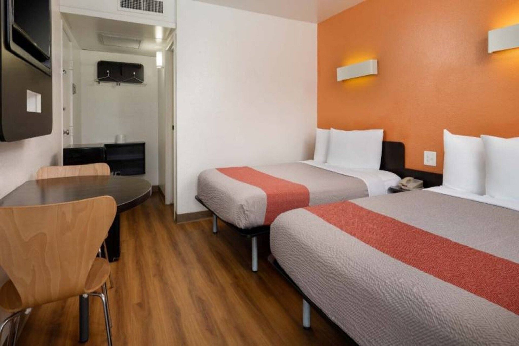 Een hotelkamer met twee bedden, een bureau en een stoel.