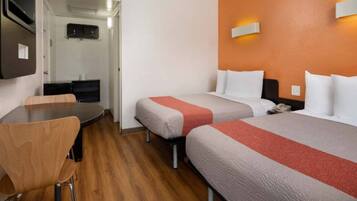 Een hotelkamer met twee bedden, een bureau en een stoel.