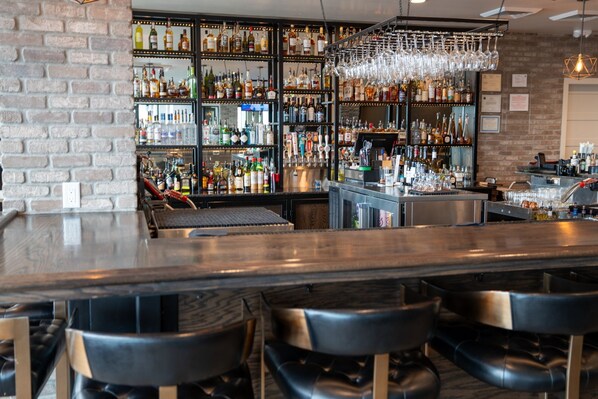 A bar area with a brick wall, shelves of liquor bottles, and black bar stools. - Pet-Friendly Guest Room w/ Wet Bar | Nr Park City (Heber City)