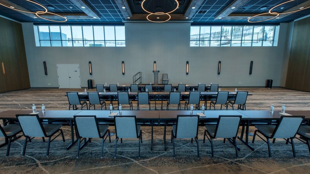 A conference room with a long table and chairs, large windows, and modern lighting fixtures.