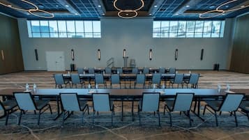A conference room with a long table and chairs, large windows, and modern lighting fixtures.