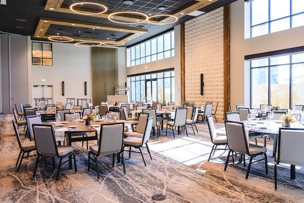 A spacious conference room with multiple tables and chairs, large windows, and a modern ceiling design. - King Guest Room with Wet Bar | Pet-Friendly (Heber City)