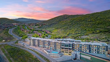 A multi-story hotel with a pool, surrounded by a hilly landscape.