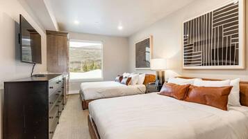 Two queen beds with leather headboards and mountain hillside view through window
