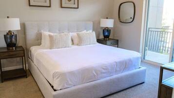 A bedroom with a large bed, two bedside tables, and a view of the outdoors through a sliding door.
