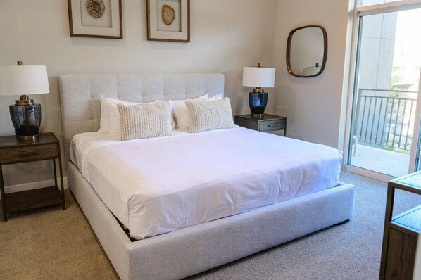 A bedroom with a large bed, two bedside tables, and a view of the outdoors through a sliding door. - Pet-Friendly King Room with Mountain Views (Heber City)