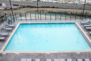 Una piscina rettangolare con bordo piastrellato, circondata da lettini e una recinzione in metallo.