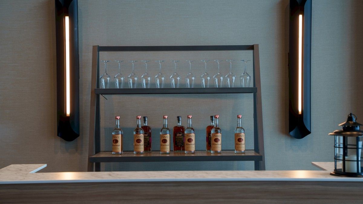 A bar area with a shelf of liquor bottles and glasses.