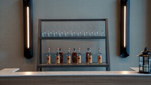 Un'area bar con un ripiano pieno di bottiglie di liquore e bicchieri.