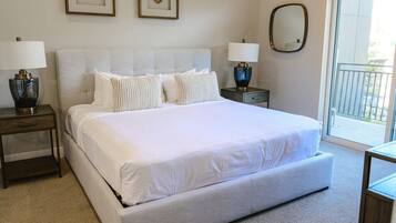 A hotel room with a large bed, two bedside tables with lamps, a mirror, and a view of the outdoors.