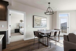 A dining area with a wooden table and chairs, a chandelier, and a large framed picture on the wall.