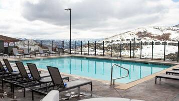 Piscina com espreguiçadeiras e vista para uma paisagem nevada.