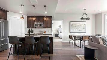 A modern kitchen with a central island, bar stools, and pendant lighting.