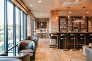 Eine Bar mit hoher Decke, freiliegenden Backsteinwänden und Blick durch große Fenster.