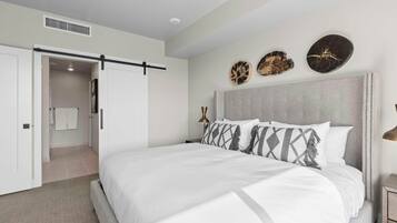 A bedroom with a large bed, a sliding door, a bedside table, and wall art.