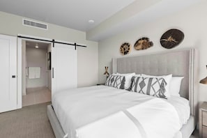 Een slaapkamer met een groot bed, een schuifdeur, een nachtkastje en decoratie aan de muur.