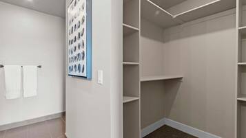 A walk-in closet with white shelving and a wall-mounted light fixture.