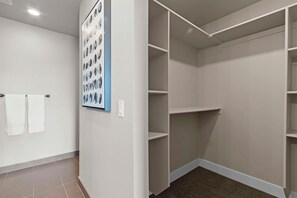 Un vestidor con estantes blancos y un aplique en la pared.