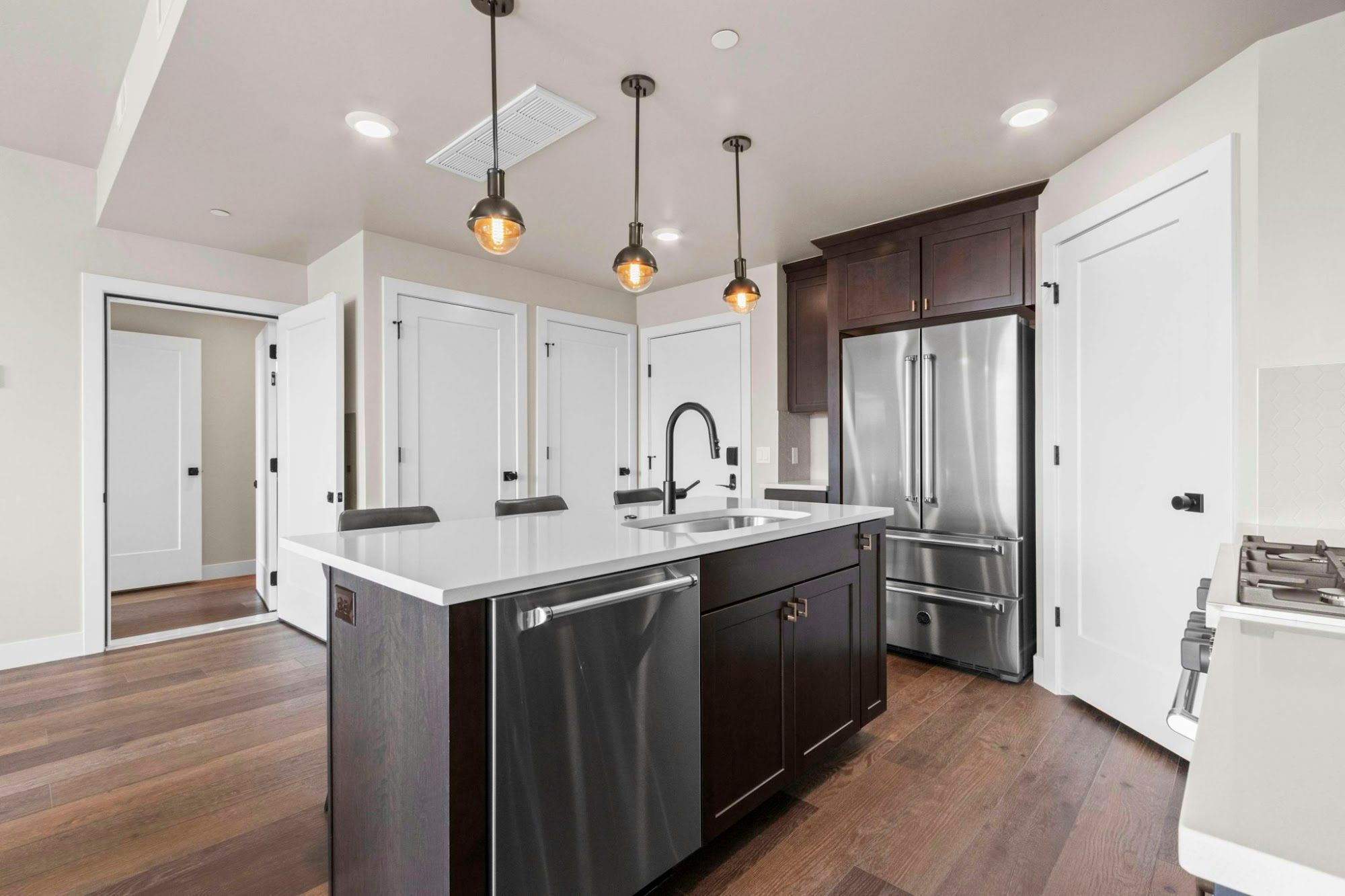 A modern kitchen with a central island, stainless steel appliances, and pendant lighting.