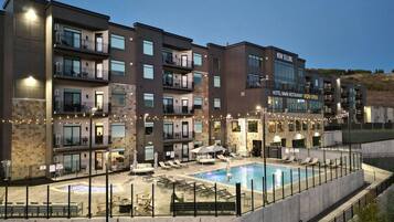 A multi-story hotel with balconies, a swimming pool, and outdoor seating.