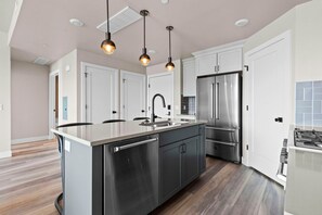 Una cocina moderna con electrodomésticos de acero inoxidable, una isla central e iluminación colgante.