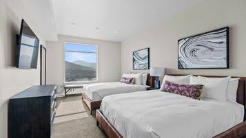 A hotel room with two beds, a desk, a TV, and artwork on the walls.