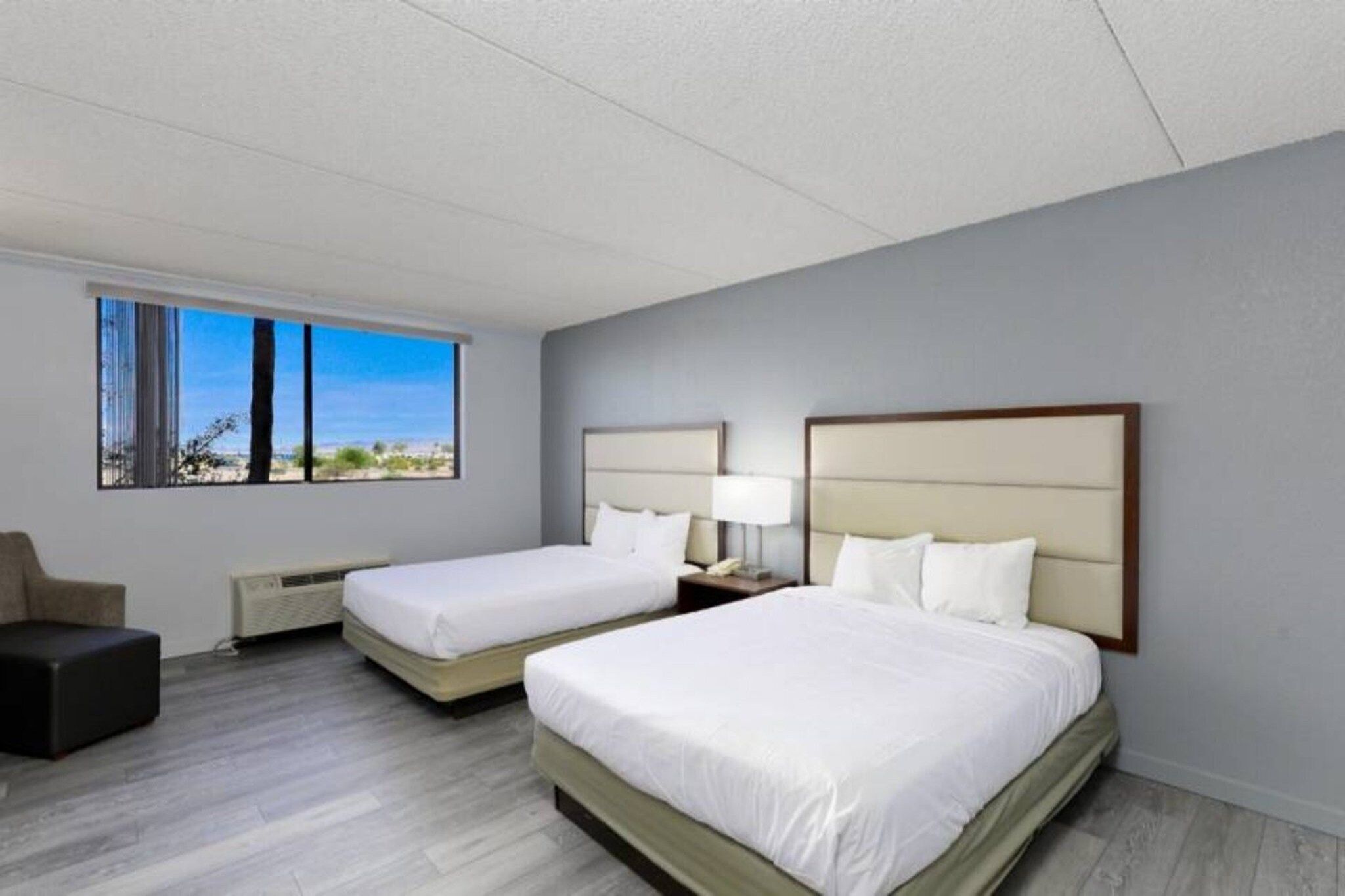 Une chambre d’hôtel avec deux lits, un bureau et une vue sur l’extérieur.