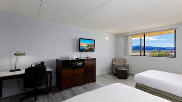 Een hotelkamer met een bed, een bureau, een stoel, een televisie en een raam met uitzicht.