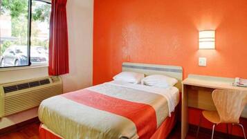 Een hotelkamer met een bed, een bureau en een stoel.