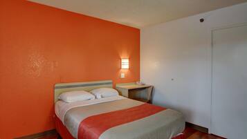 Habitació d'hotel amb llit, taula de nit i aplíc de paret.