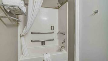 A bathroom with a bathtub, a shower, and a toilet. There are grab bars installed for safety.