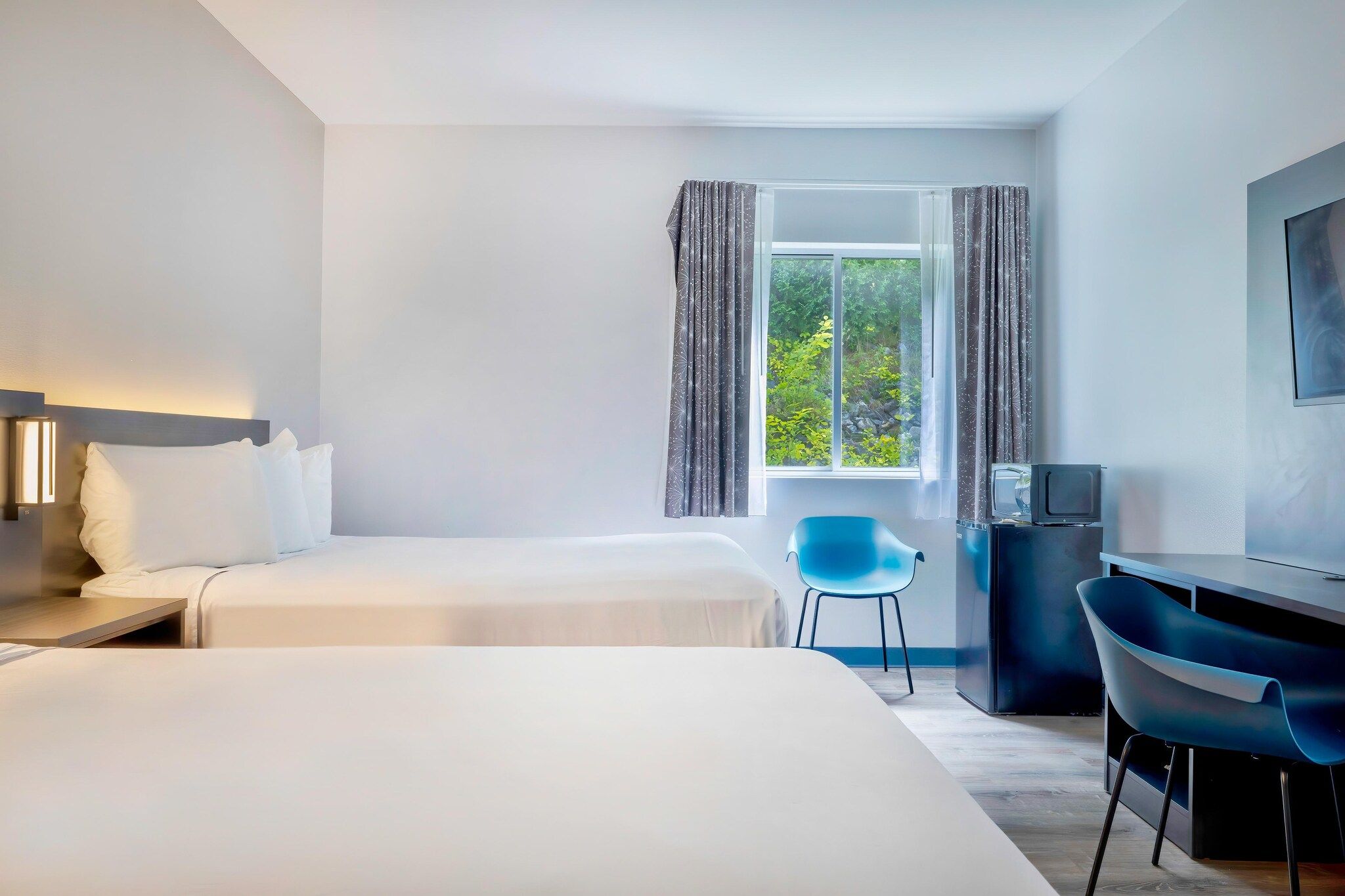 Een hotelkamer met twee bedden, een bureau, een stoel en een televisie.