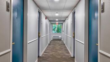 Un corridoio di un albergo con porte su entrambi i lati, una moquette decorata e un soffitto con faretti.