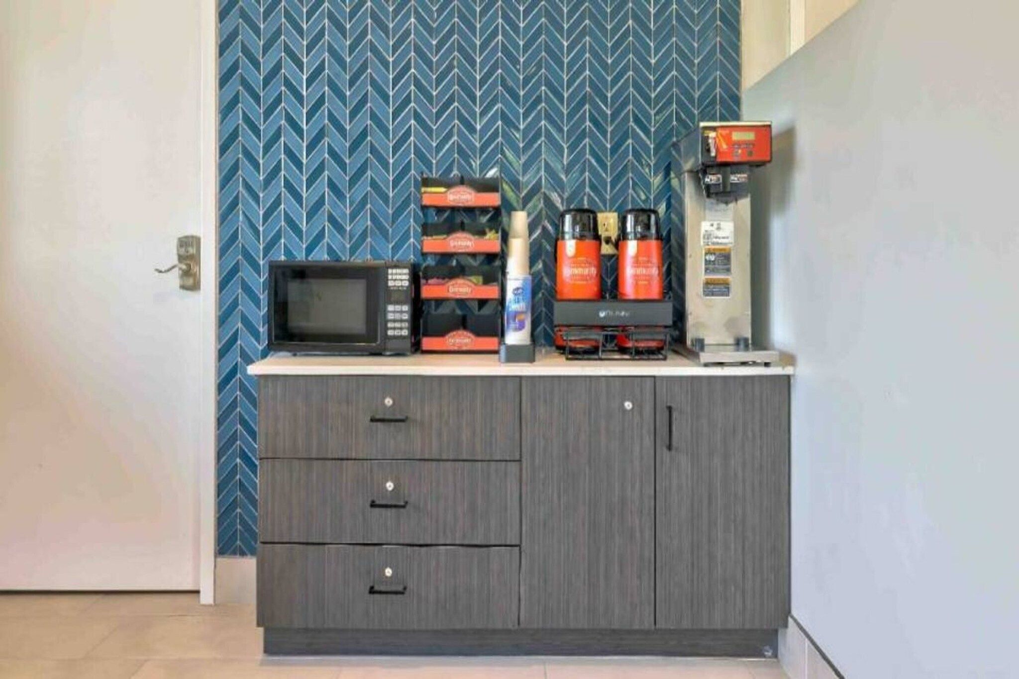 A kitchenette with a microwave, coffee maker, and storage cabinets.
