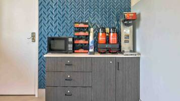 A kitchenette with a microwave, coffee maker, and storage cabinets.
